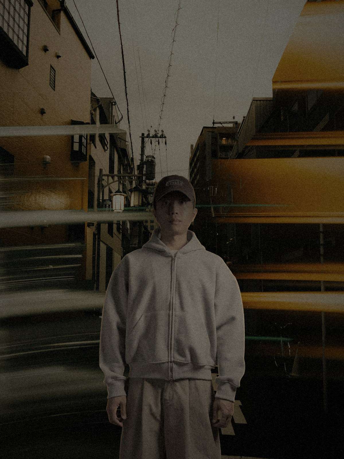 Model in a heather-gray hooded jacket standing on a street